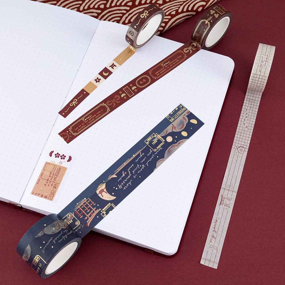Torii washi tape rolls on white bullet journal pages on red background