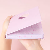 Tsuki Four Seasons: Spring Collector’s Edition 2022 Bullet Journal held in hands at an angle in light pink background