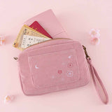 Tsuki ‘Sakura Journey’ Travel Pouch with travel essentials and Tsuki ‘Sakura Journey’ Limited Edition Travel Notebook inside with cherry blossoms on pink background