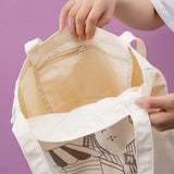 Hands holding up a canvas tote bag showing the inside