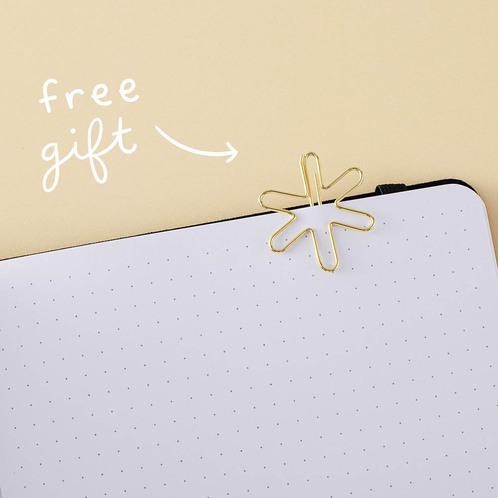 Star-shaped gold paperclip clipped on a bullet journal page with the words “free gift” in white on yellow background