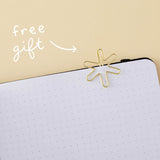 Star-shaped gold paperclip clipped on a bullet journal page with the words “free gift” in white on yellow background