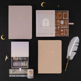 Flatlay of Tsuki ‘Moonlit Alchemy’ collection including Tsuki ‘Moonlit Alchemy’ stamps , Stardust Dawn bullet journal, Moonlit Dusk bullet journal and Moonlit Alchemy washi tapes
