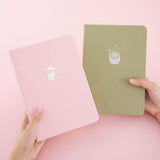 Tsuki ‘Ichigo’ Limited Edition Boba Bullet Journal and Tsuki ‘Matcha Matcha’ Limited Edition notebook held in hands in light pink background