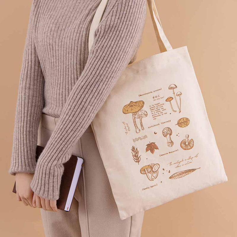 Tsuki ‘Vintage Kinoko’ Tote Bag held on model’s arm with Tsuki ‘Nara’ Limited Edition Bullet Journal in beige background