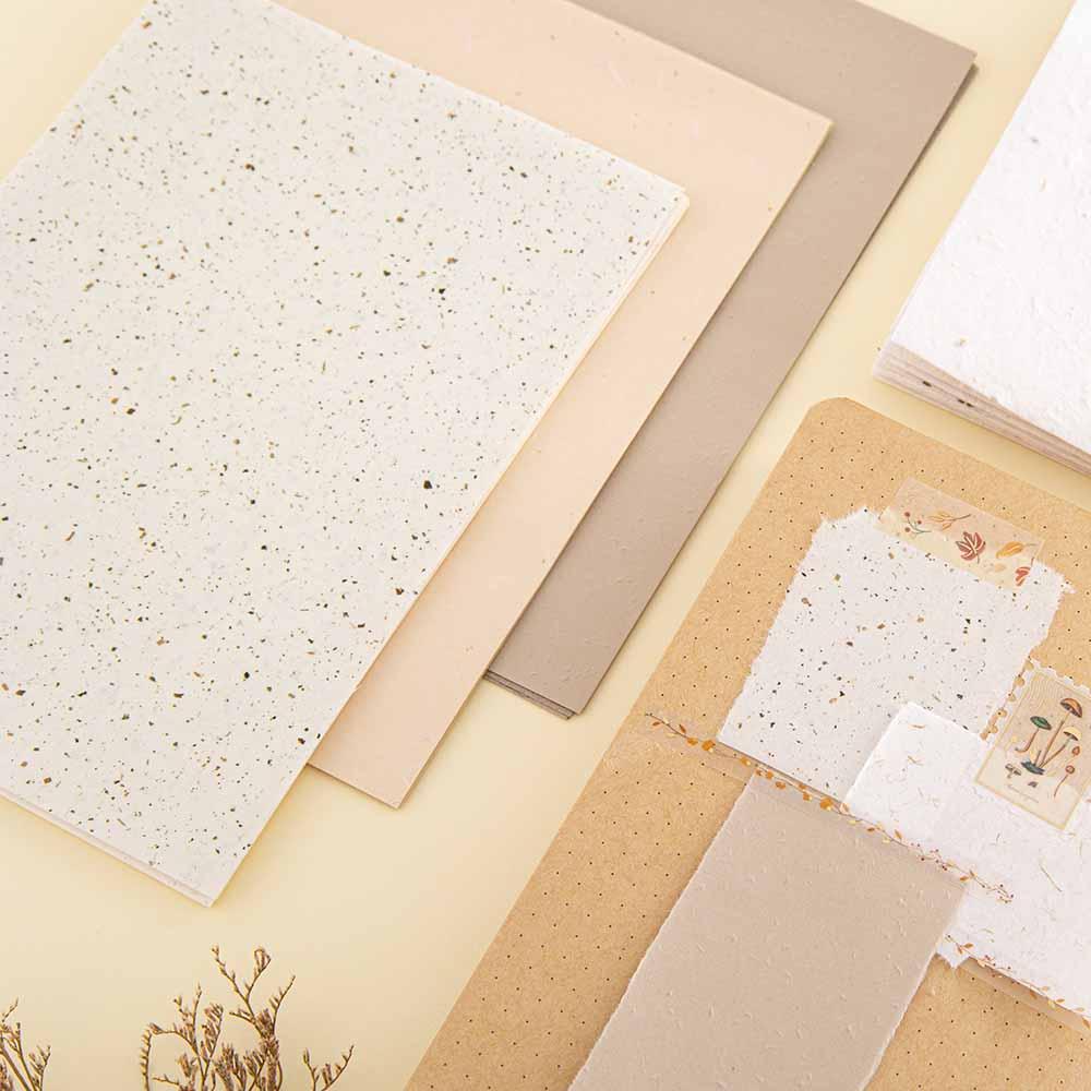 Close up of Tsuki Mixed Scrapbook Paper Pack with open Tsuki Kraft Paper Limited Edition Bullet Journal on cream background