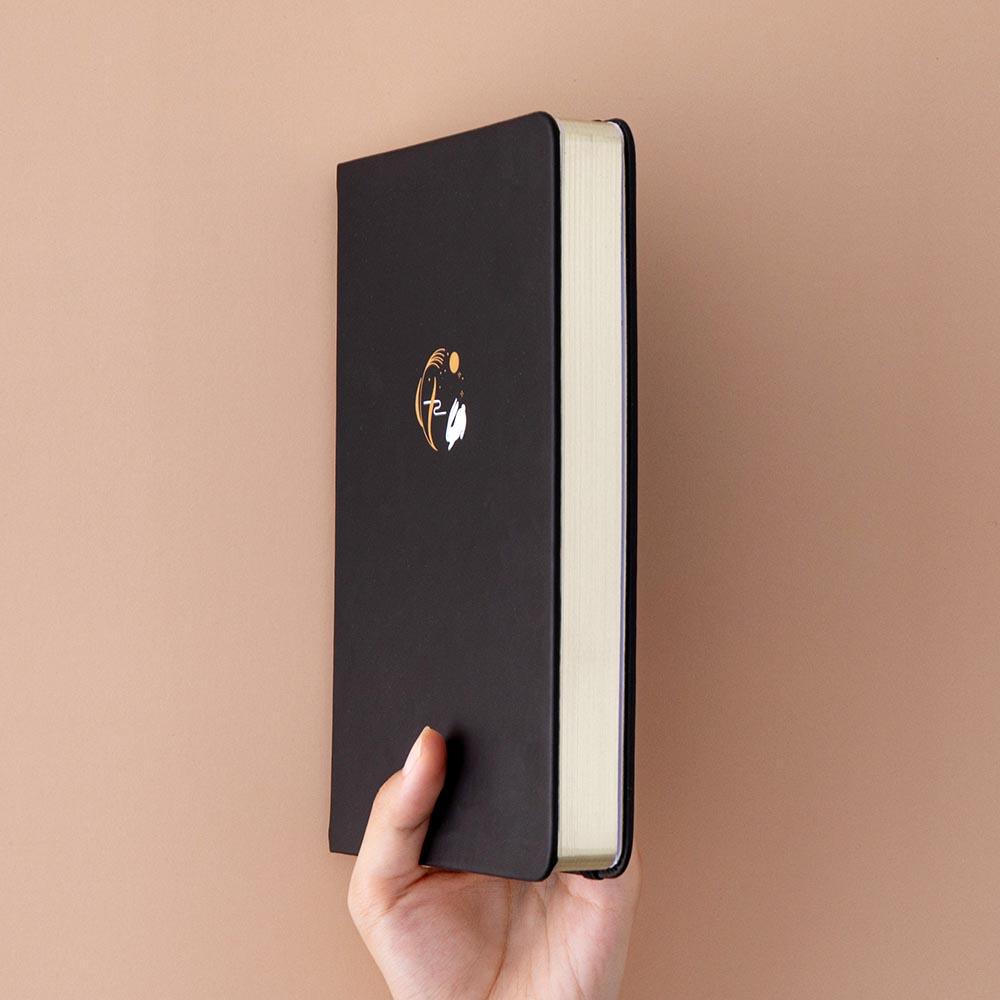 Tsuki ‘Moonlit Wish’ Limited Edition Bullet Journal held in hand at spine angle in light brown background