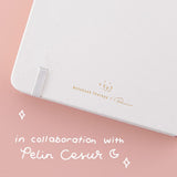 Close up of the back cover of Tsuki Cloud White ‘Flutter + Dream’ Limited Edition Bullet Journal by Notebook Therapy x Pelinkan on pastel pink background