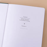 Close up of the open front page of Tsuki ‘Midnight Garden’ Limited Edition Bullet Journal on beige background