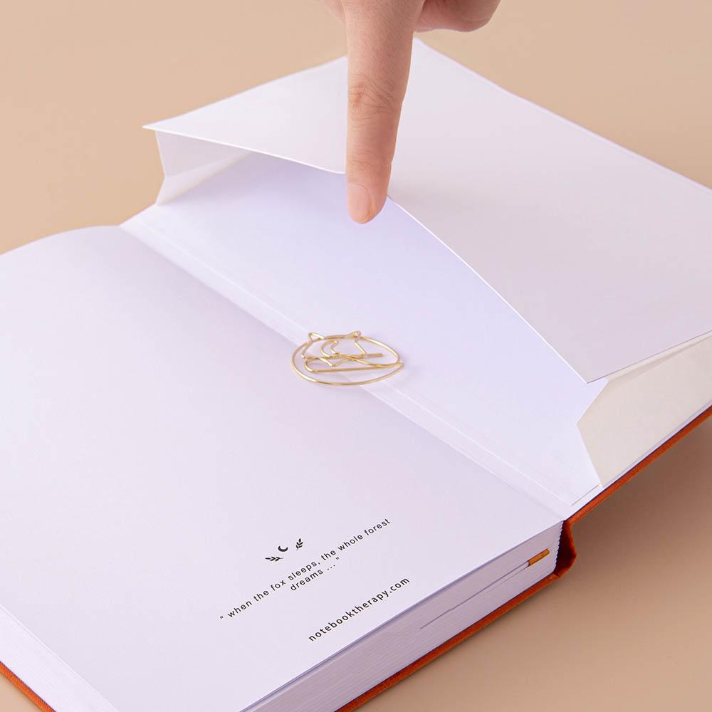 Open back page pocket of Tsuki ‘Kitsune’ Limited Edition Fox Bullet Journal held in hand with free paperclip gift on beige background