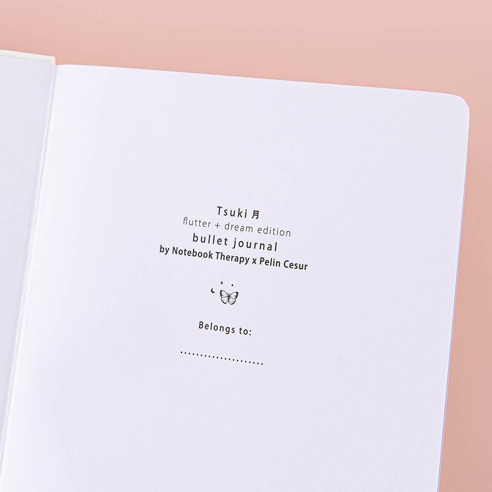 Close up of the open front page of Tsuki Cloud White ‘Flutter + Dream’ Limited Edition Bullet Journal by Notebook Therapy x Pelinkan on pastel pink background
