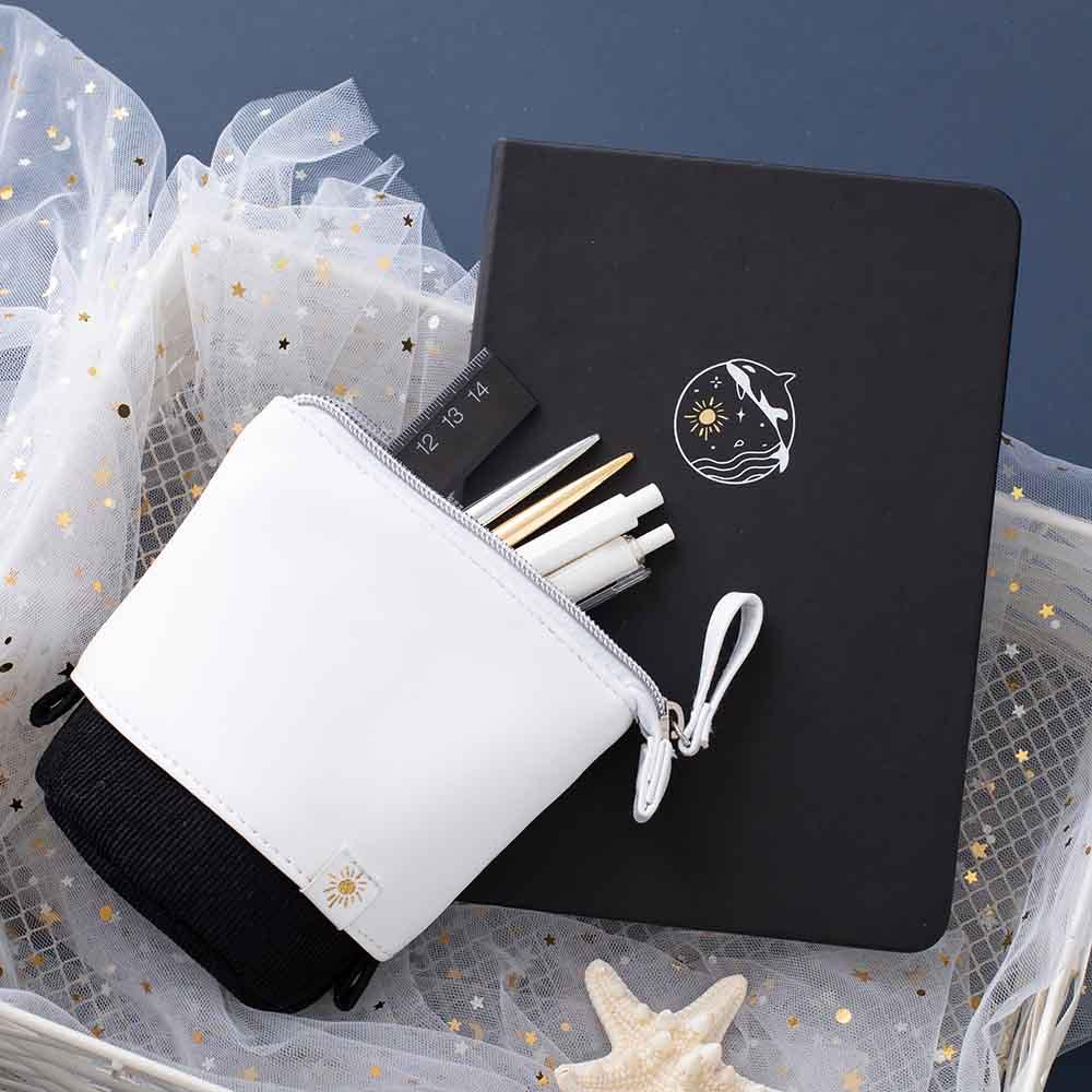 Tsuki Black Paper Limited Edition Hardcover Bullet Journal in Playful Orca with Tsuki Ocean Edition Pop-Up Pencil Case in Orca Black in white wooden basket with star netting on dark blue background