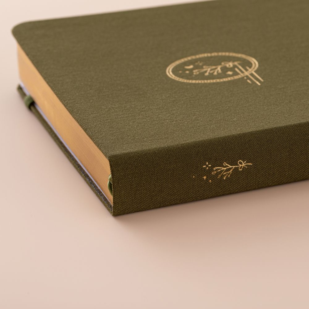 Close up of the gold details on the spine of a green linen bullet journal